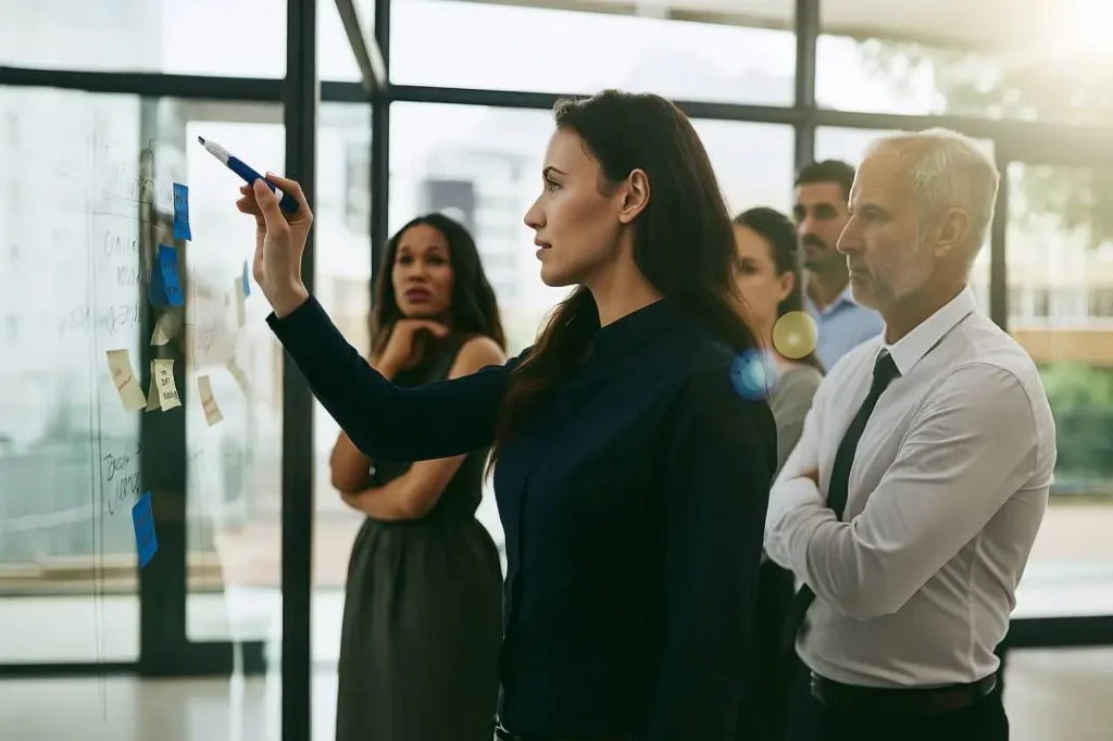 Team planning session for an internet marketing strategy, with a woman leading a discussion on a glass board.